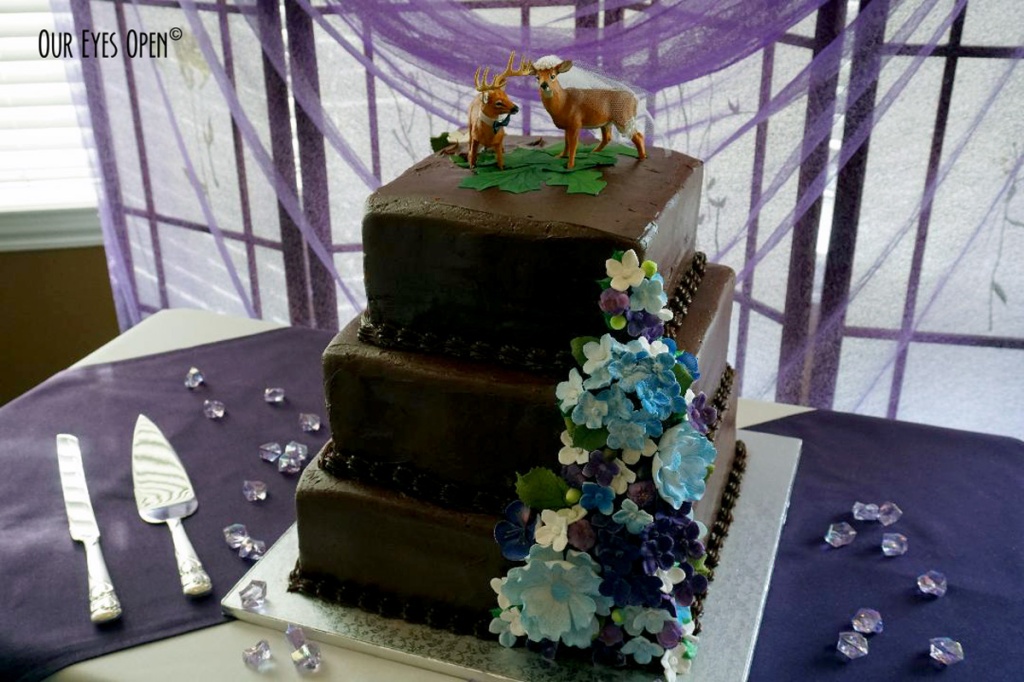 Chocolate wedding cake with blue flowers & buck and doe topper.